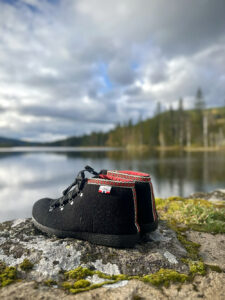 Afterski fra Nesnalobben – varme og komfortable ullfilt-sko med solid såle og mykt fôr. Perfekte etter en dag i bakken, foran peisen eller ut i snøen etter mer ved. Afterskisko fra Nesnalobben stående på en bakke foran et vann