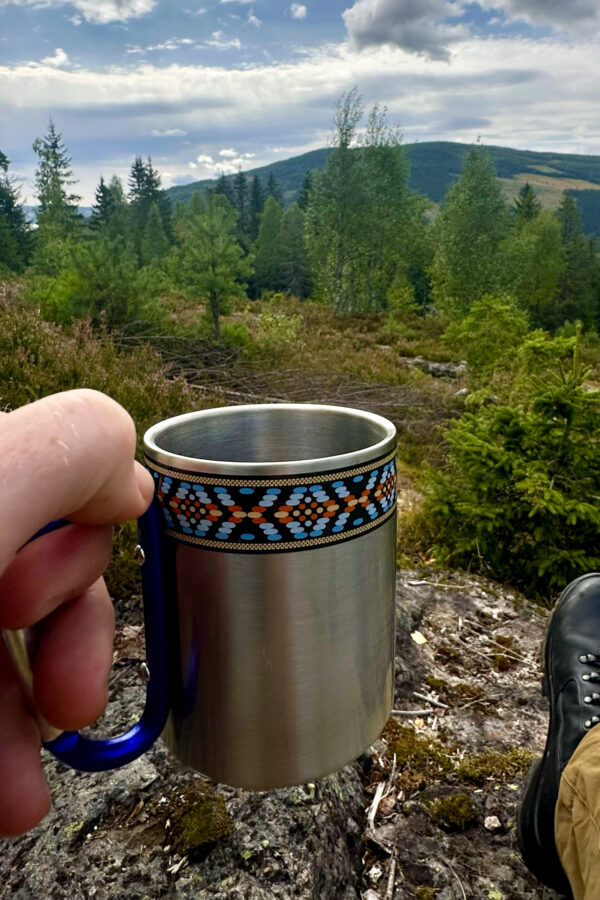 Turkopp i rustfritt stål med blå hank, karabinkrok og pyntekant med Nesnalobben-mønster.