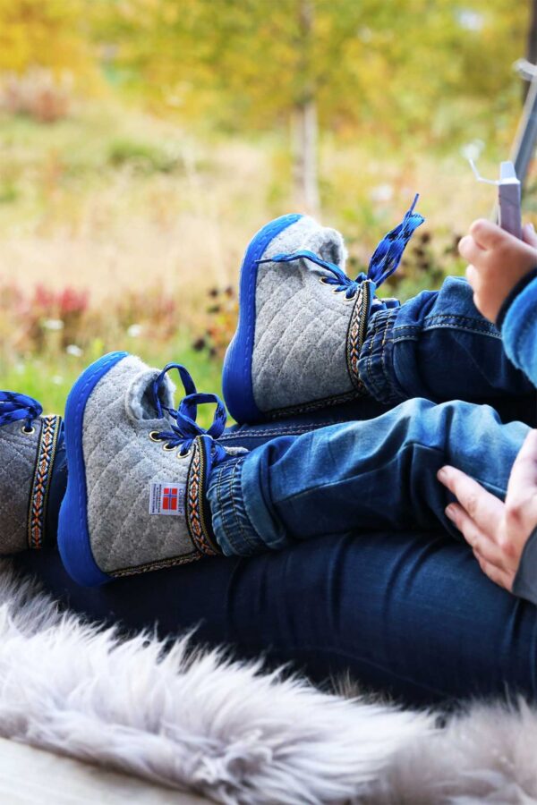 Barn på foreldrers fang, med Nesnalobben vintersko på, laget i ullfilt