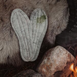 Håndlagde innleggssåler i bjørkenever og tovet ull fra Sara Duodji i Karasjok, vist på bord av naturmaterialer.