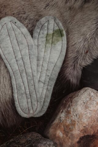 Håndlagde innleggssåler i bjørkenever og tovet ull fra Sara Duodji i Karasjok, vist på bord av naturmaterialer.