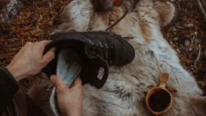 Håndlagde innleggssåler i bjørkenever og tovet ull fra Sara Duodji i Karasjok, vist på bord av naturmaterialer.